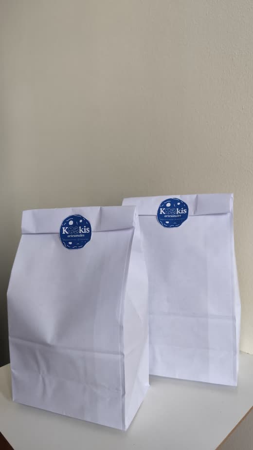 Dos bolsas de papel blancas cerradas con el sticker azul de Kookis.